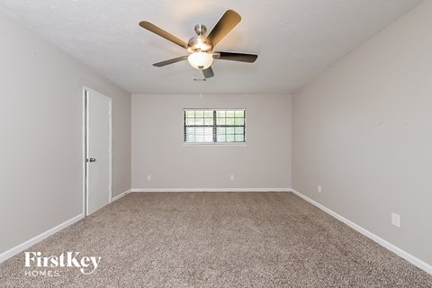 the spacious living room with ceiling fan and carpet