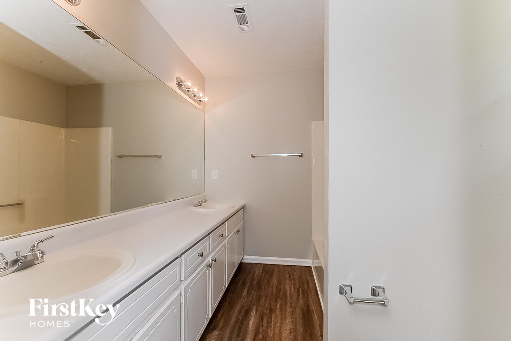 a bathroom with white cabinets and a large mirror