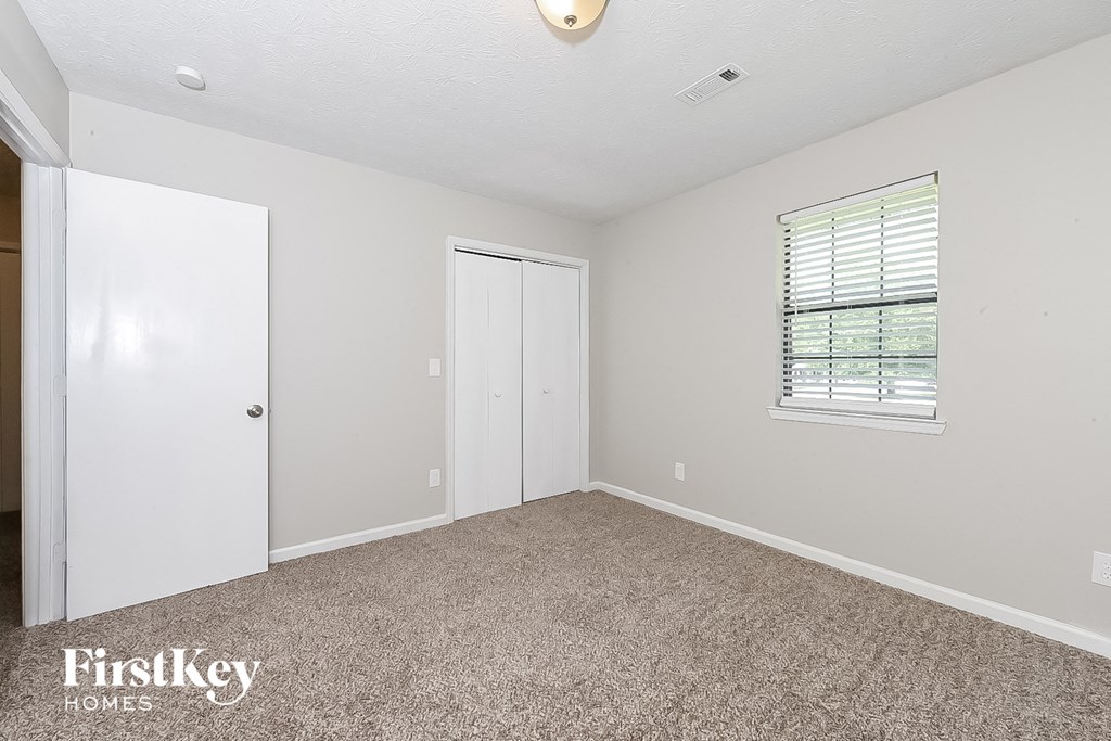 a bedroom with a carpeted floor and a door to a closet