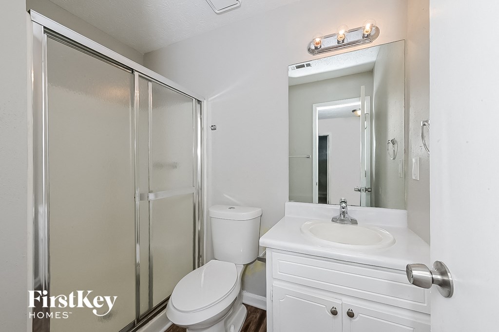 a white bathroom with a shower toilet and sink