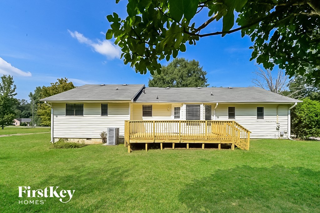 a small white house with a deck in a grass field