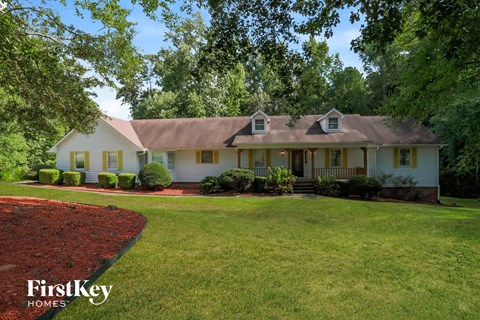 a white house with a lawn and trees