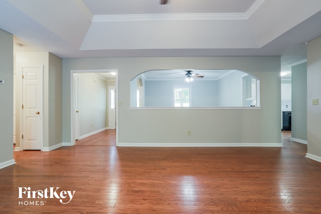 an empty living room with wood floors and a ceiling fan