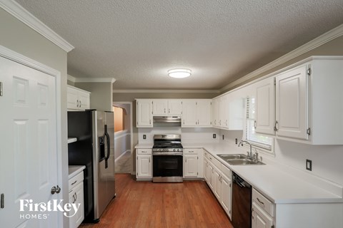 a kitchen with white cabinets and black appliances and a wooden floor