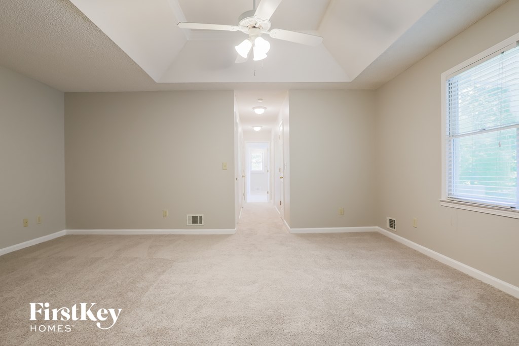 an empty living room with a ceiling fan and a large window
