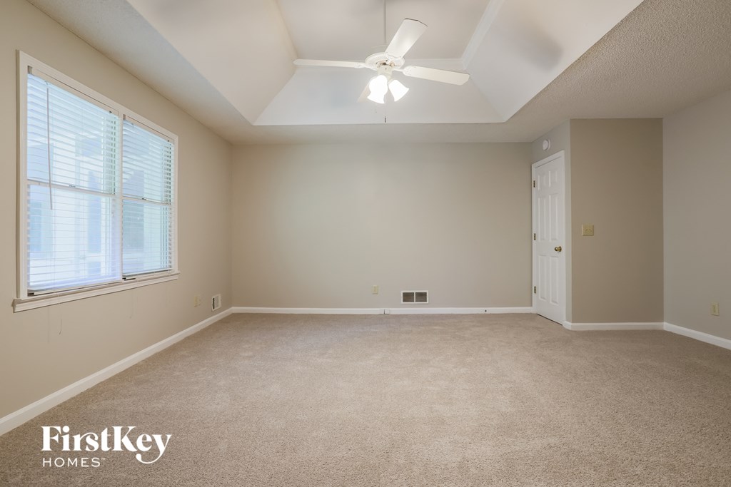 a bedroom with a ceiling fan and a large window