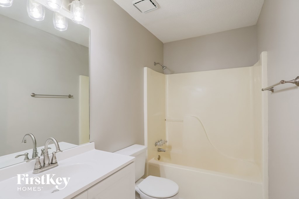 a white bathroom with a white sink and a shower and a toilet