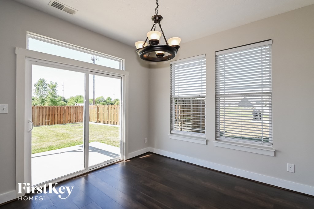 an empty living room with a sliding glass door to a backyard