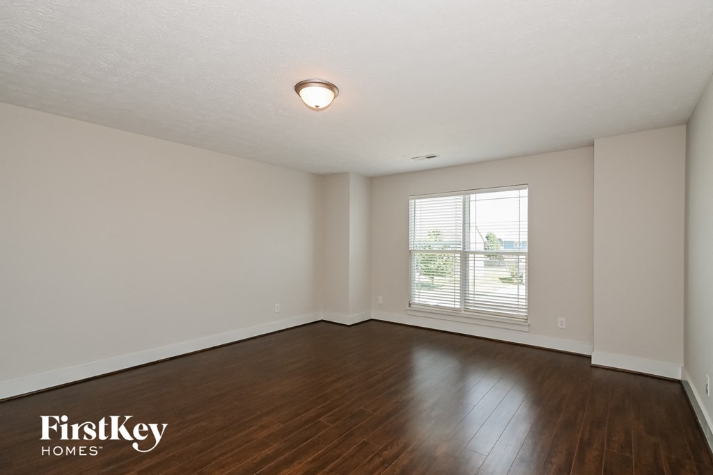 an empty living room with wood floors and a window