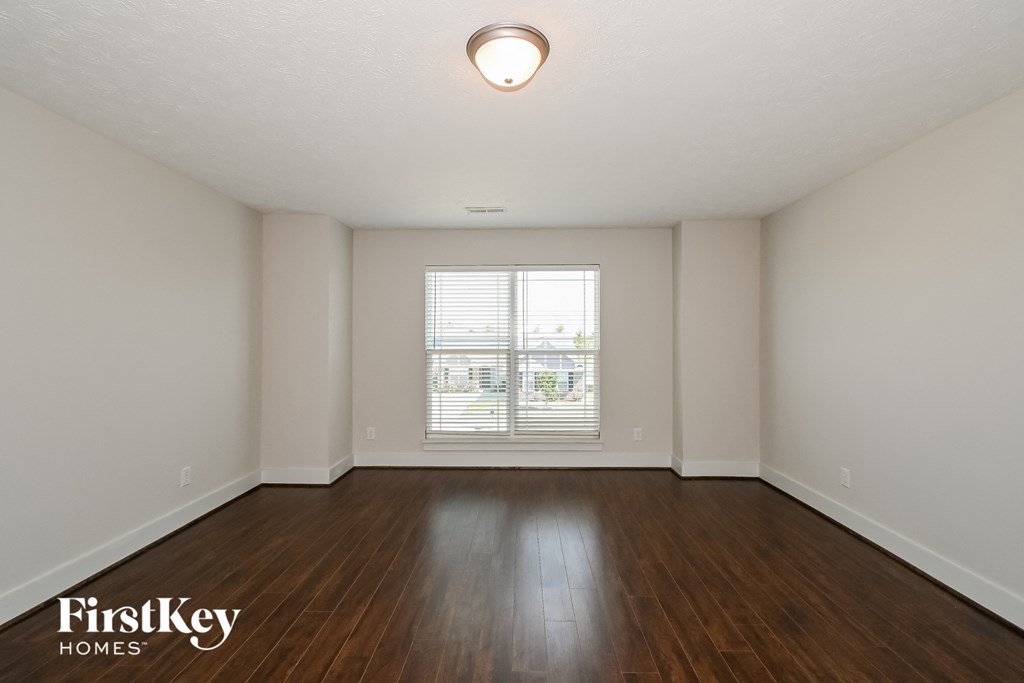 the spacious living room with wood flooring and a large window
