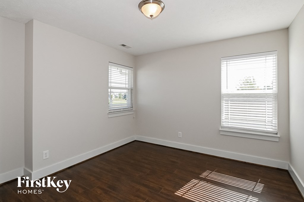 the spacious living room with wood flooring and two windows