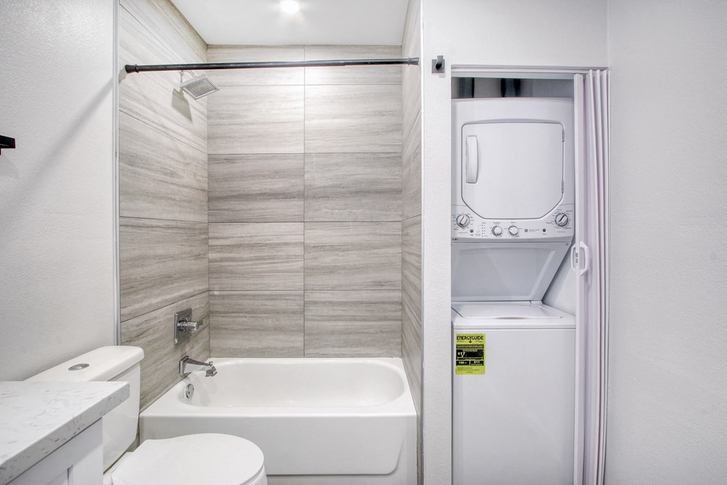 a bathroom with a sink toilet and a tub and a washer and dryer