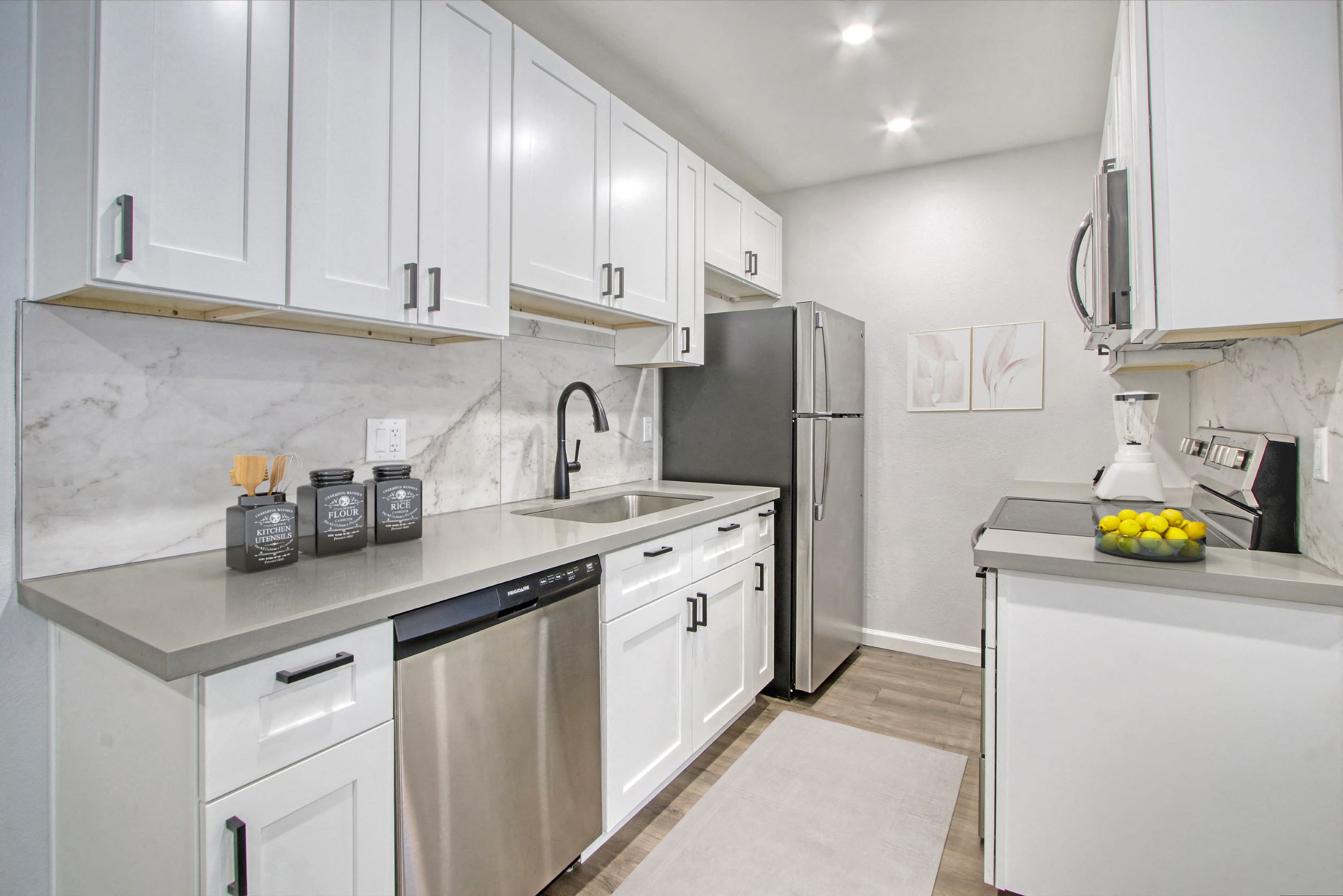 a white kitchen with stainless steel appliances and white cabinets
