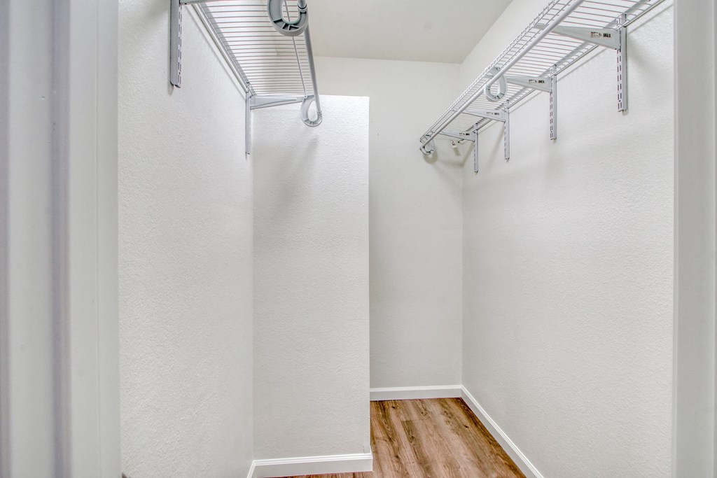 an empty room with white walls and a closet with hanging racks