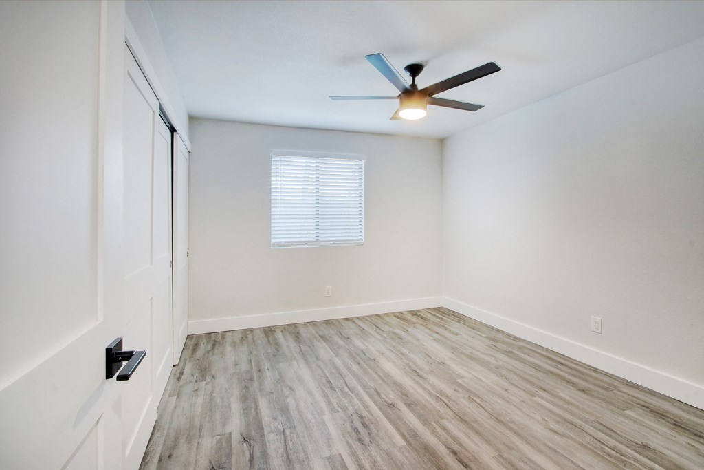 an empty room with white walls and a ceiling fan