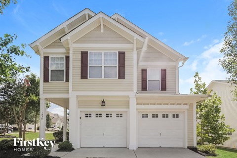 the front of a white house with two garage doors