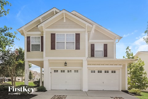a white house with two garage doors in front of it