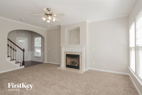 an empty living room with a fireplace and a ceiling fan