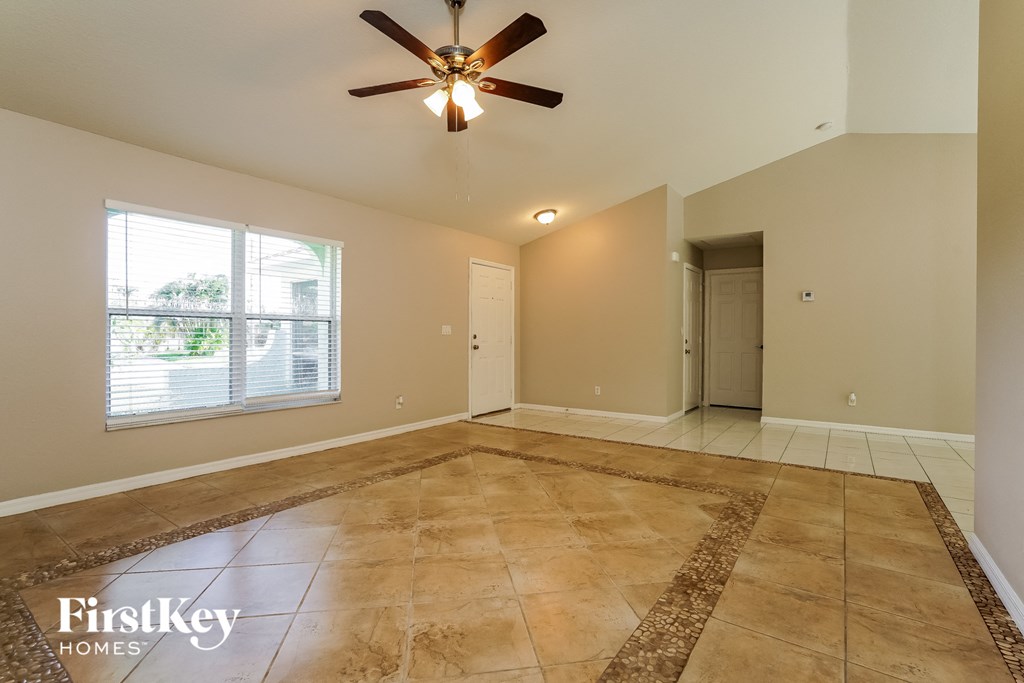 the spacious living room with tiled floors and a ceiling fan