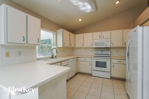 a kitchen with white cabinets and appliances and a white counter top