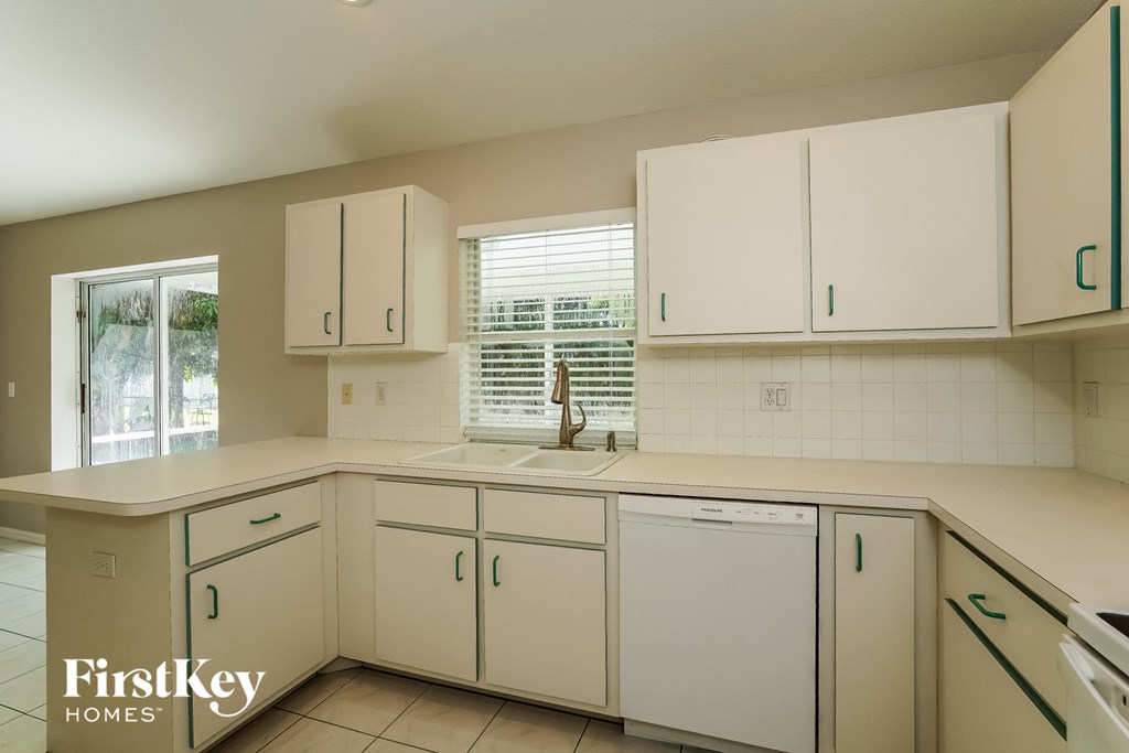 a kitchen with white cabinets and a sink and a window