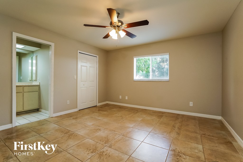 an empty living room with a ceiling fan and tiled floors