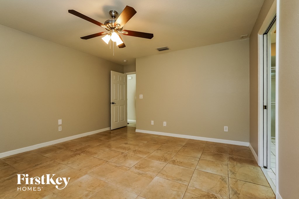 a empty living room with a ceiling fan and tiled floors