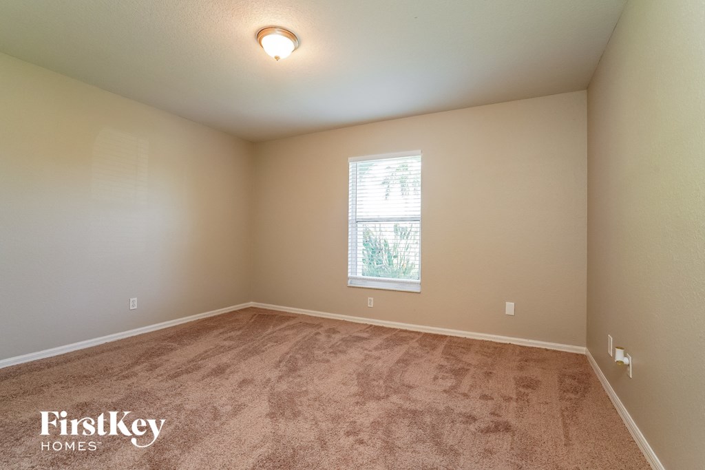 the spacious living room with carpeted floors and a window