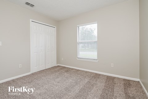 a bedroom with carpet and a door and a window