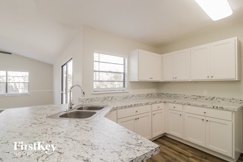 a kitchen with white cabinets and marble counter tops and a sink