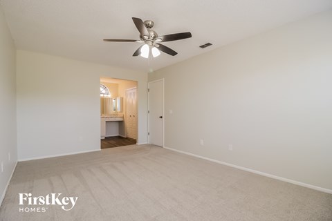 a spacious living room with white carpet and a ceiling fan