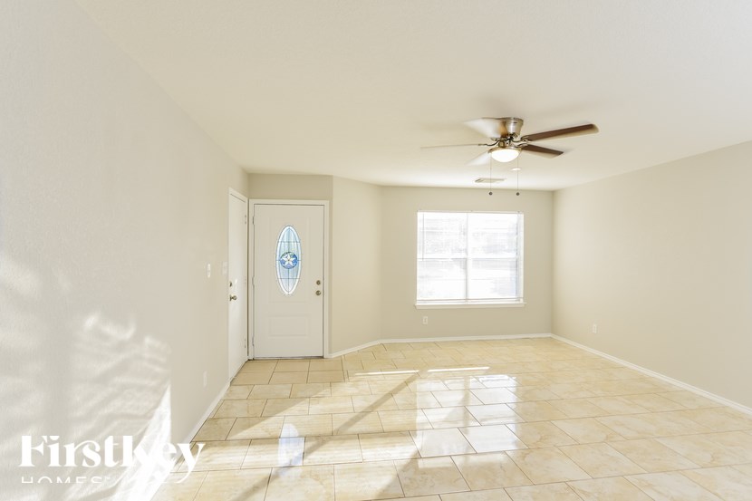 A room with a ceiling fan and a door with a stained glass window.
