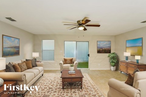 A living room with a couch, a coffee table, and a ceiling fan.