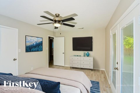 A bedroom with a bed, dresser, and a ceiling fan.