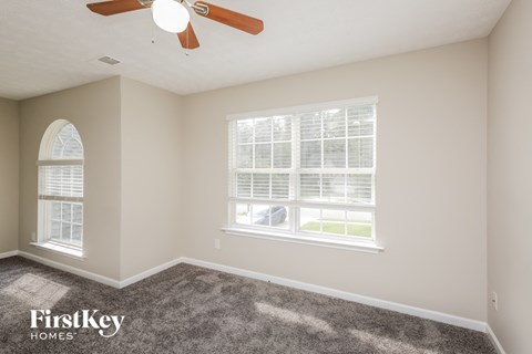a bedroom with two windows and a ceiling fan