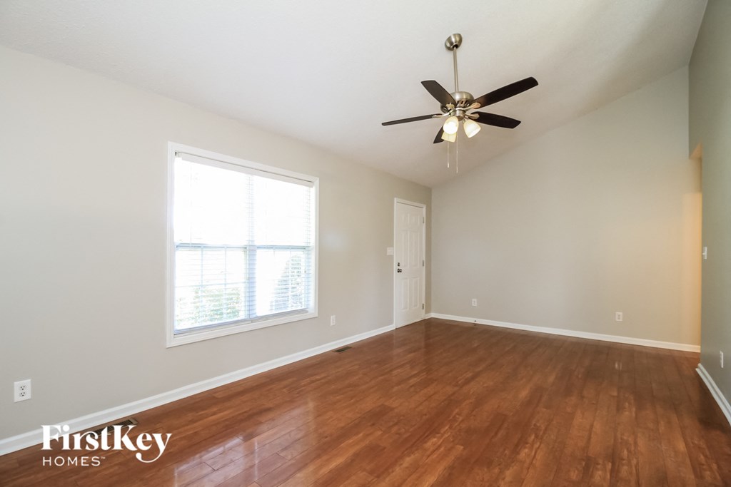 A room with a ceiling fan and wooden floors.