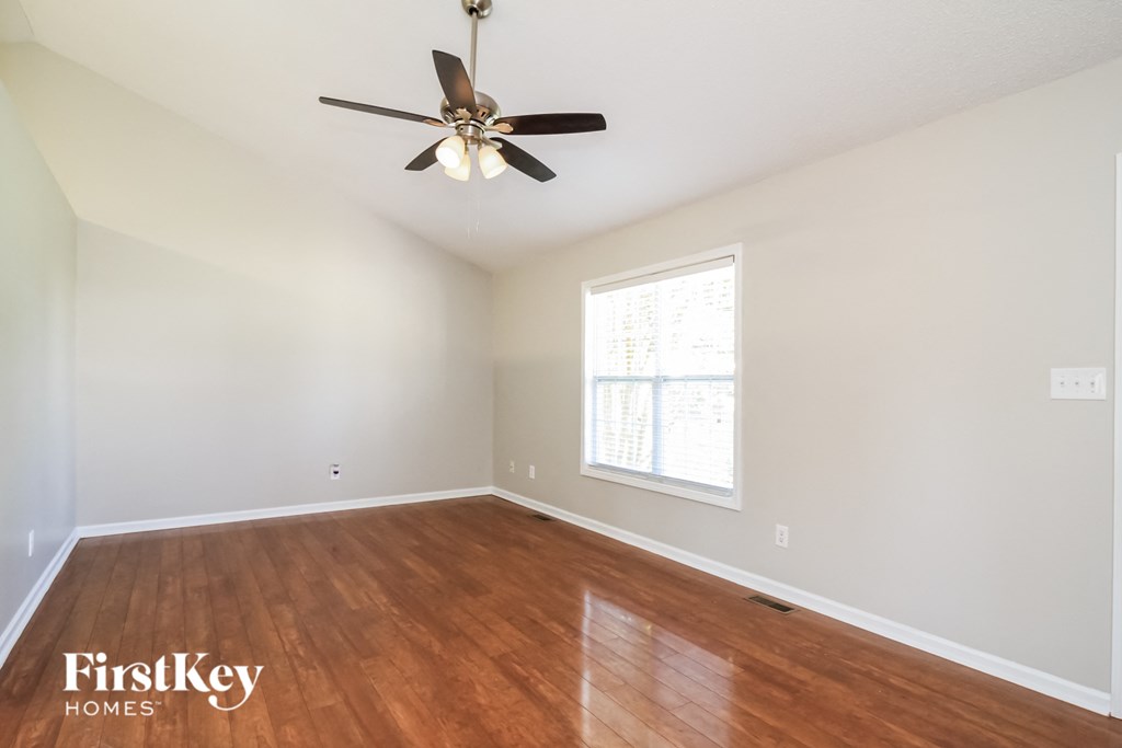 A room with a ceiling fan and wooden flooring.