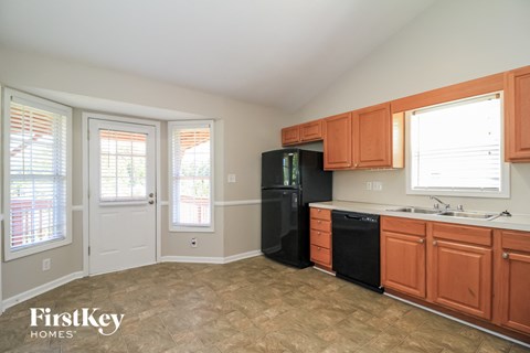 A kitchen with wooden cabinets and a black fridge.
