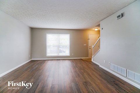 A room with wooden floors and a window with blinds.