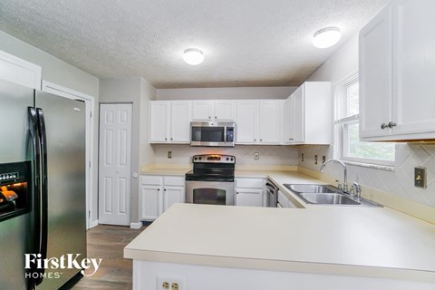 A kitchen with white cabinets and a refrigerator.