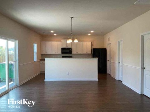 A spacious kitchen with white cabinets and a wooden floor.