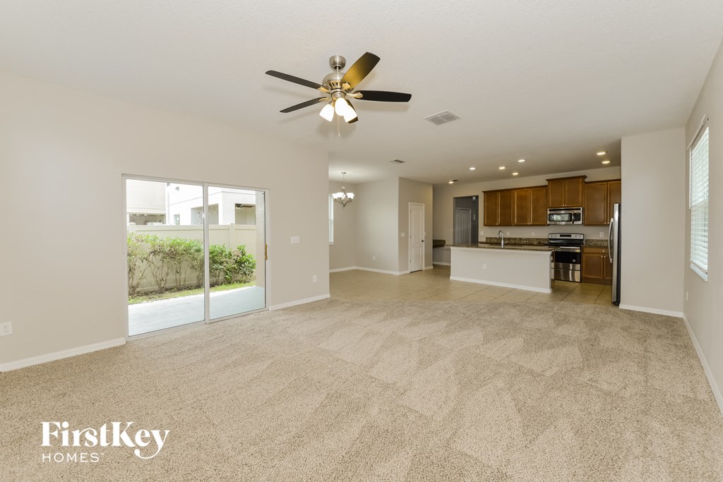 a spacious living room and kitchen with a ceiling fan