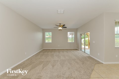 a spacious living room with a ceiling fan and a carpet