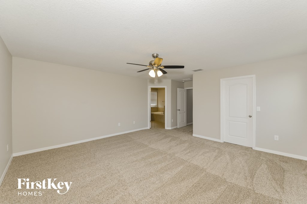 a spacious living room with carpet and a ceiling fan