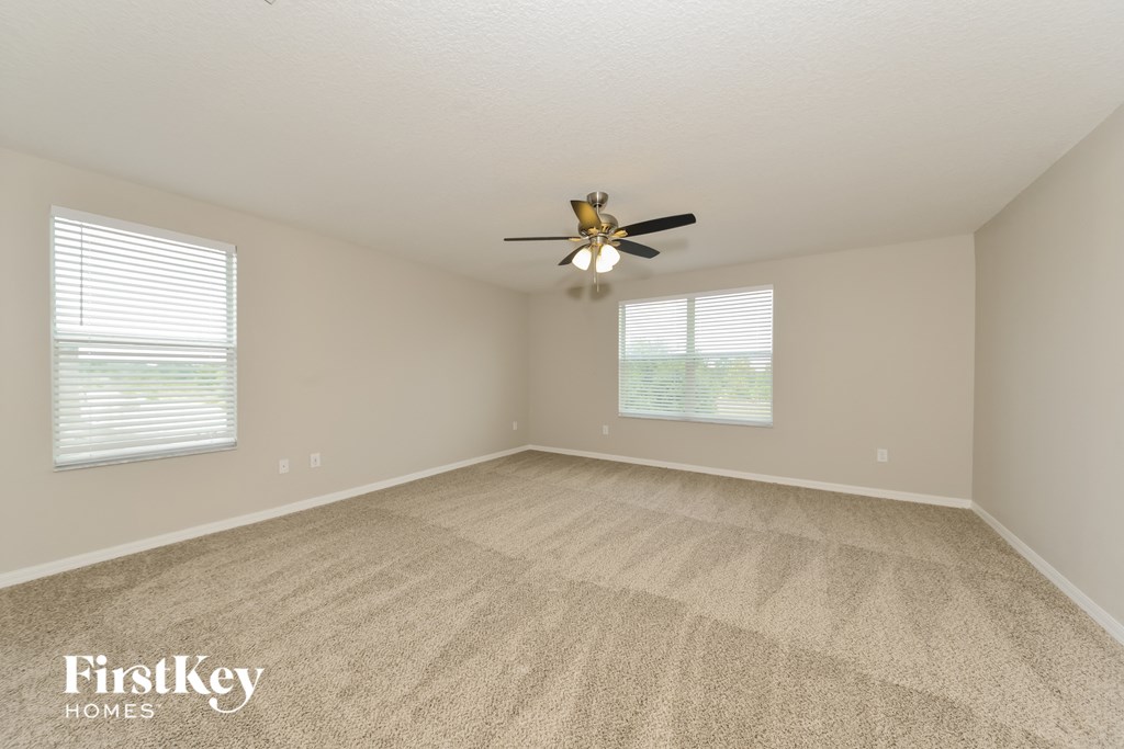 a spacious living room with carpet and a ceiling fan