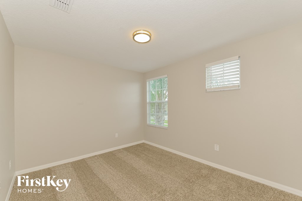 a spacious living room with beige carpet and a window