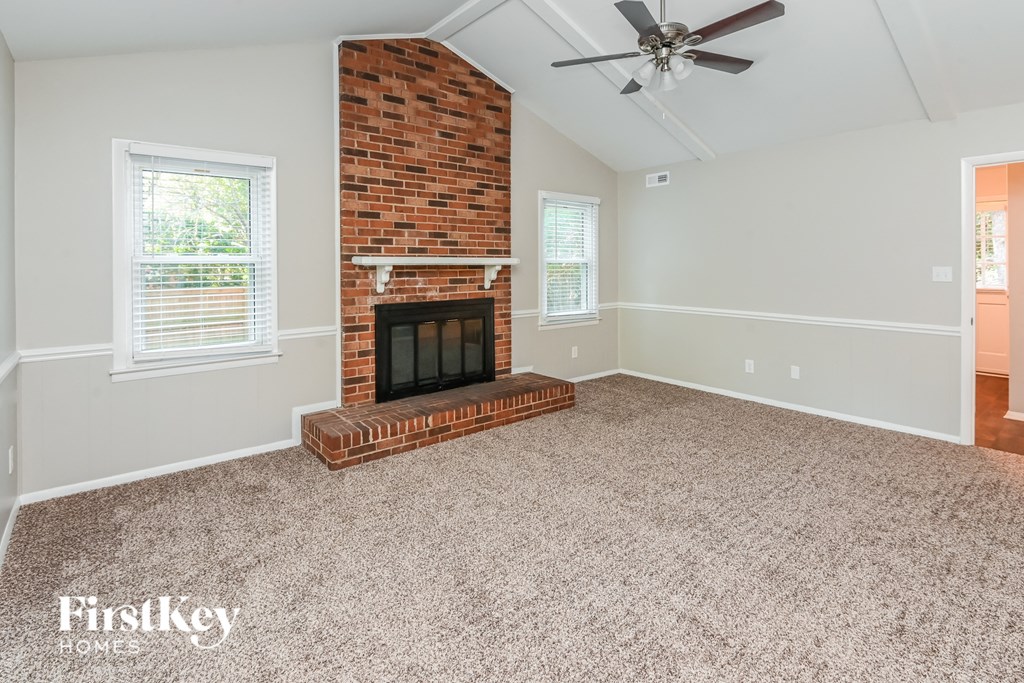 an empty living room with a brick fireplace and a ceiling fan
