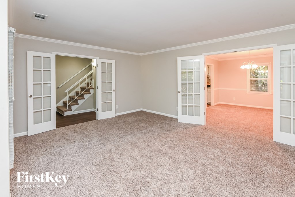 a empty living room with a carpeted floor and a staircase