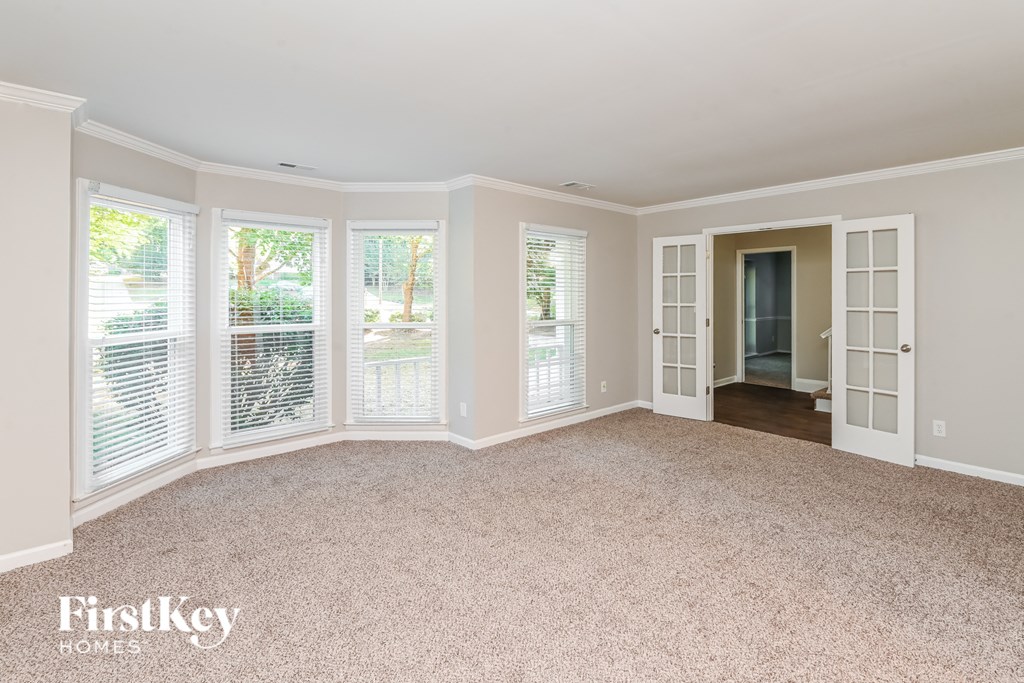 an empty living room with large windows and carpet