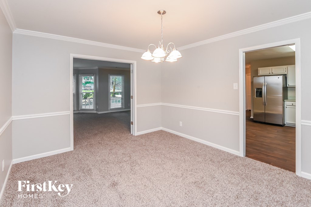 a spacious dining room with white walls and carpet